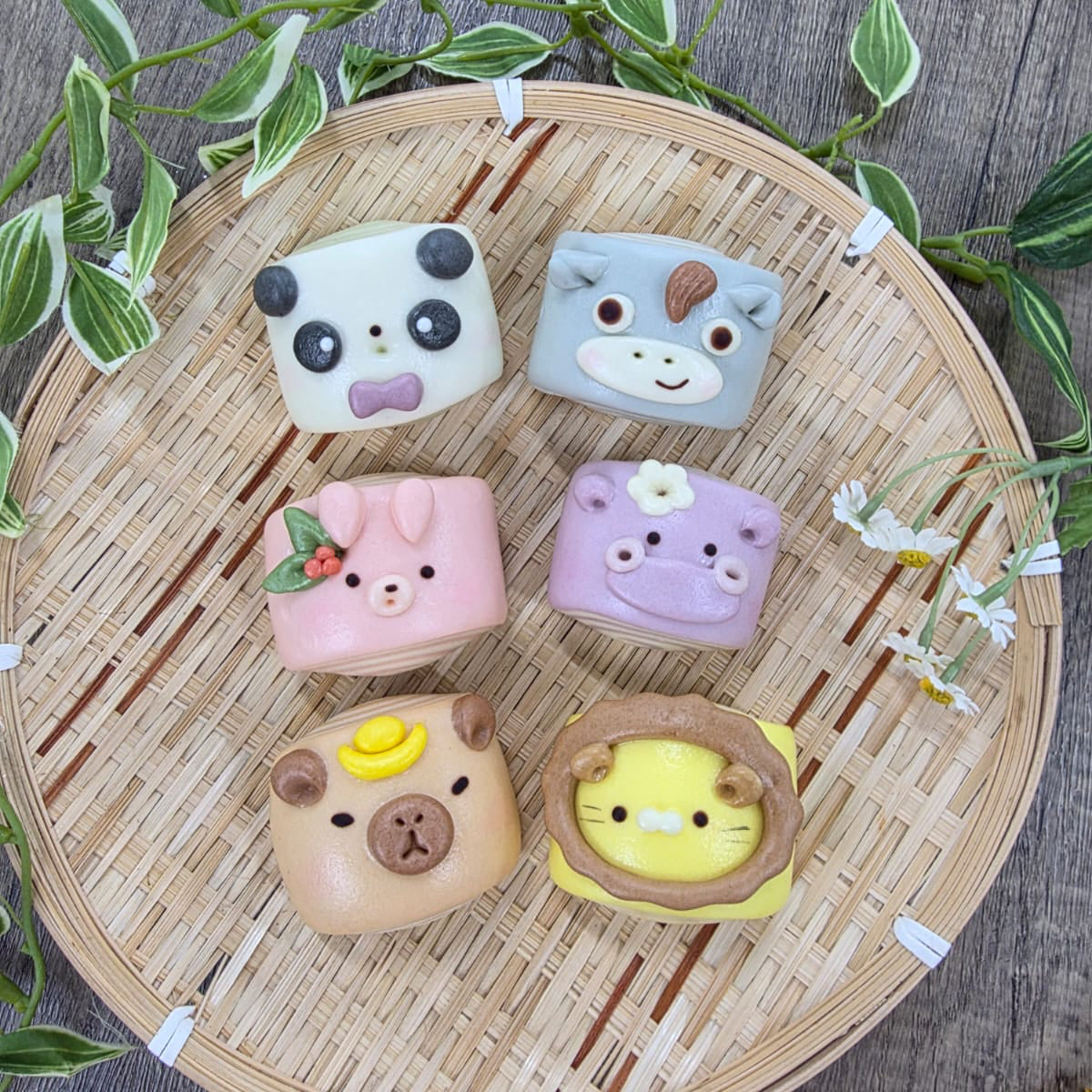 Six animal-shaped steamed buns on a bamboo tray with a wooden background