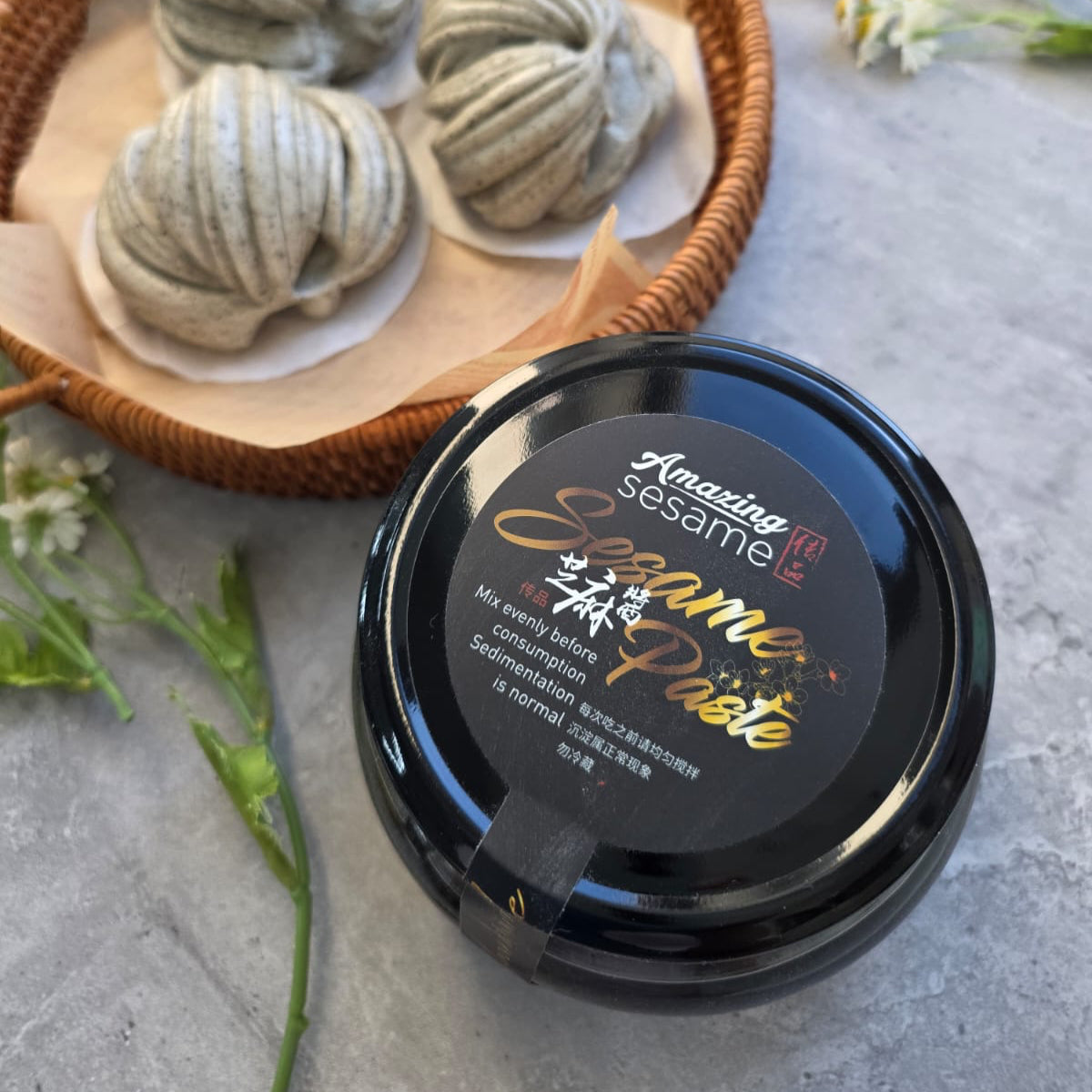 Black sesame paste container with sesame balls on a wooden tray in the background